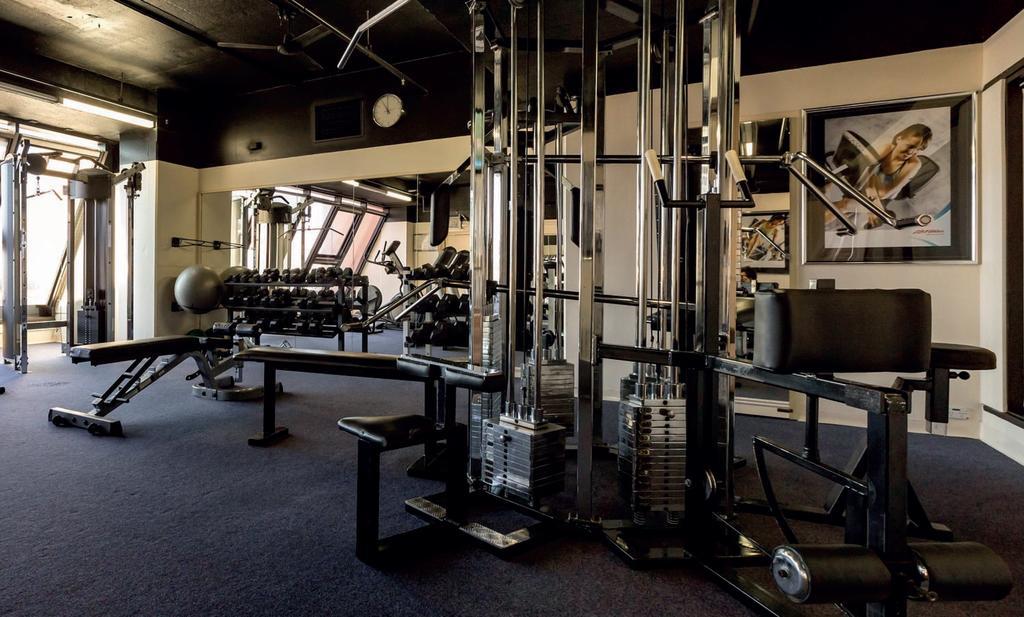 Stamford Grand Adelaide Hotell Glenelg Exteriör bild The photo shows a gym interior with several pieces of exercise equipment. In the foreground, there is a multi-station machine that features various pulleys and weights. To the side, there are benches and free weights, including dumbbells. The gym has